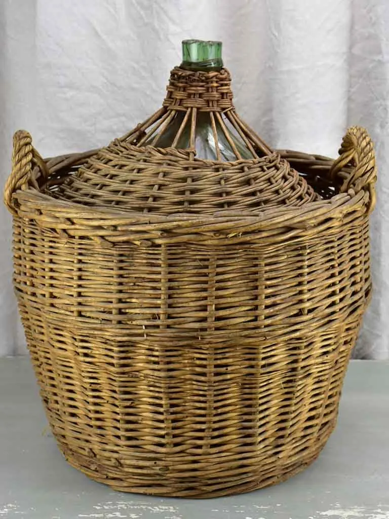 Very large antique French demijohn in a basket