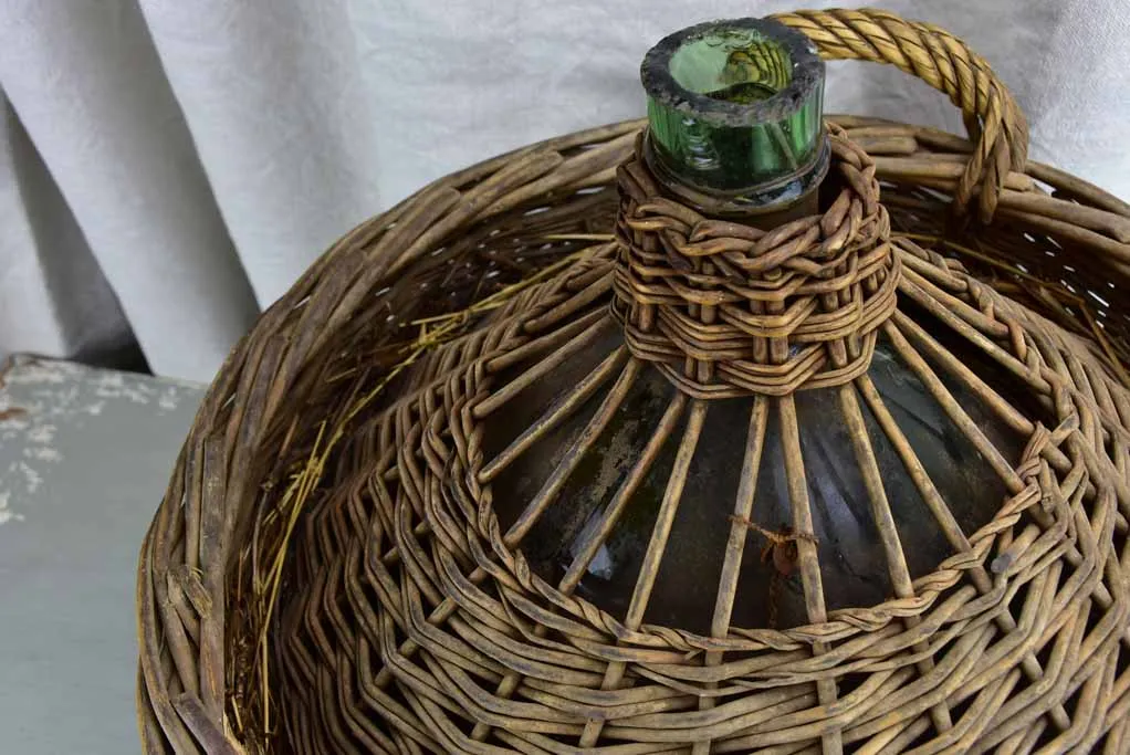 Very large antique French demijohn in a basket