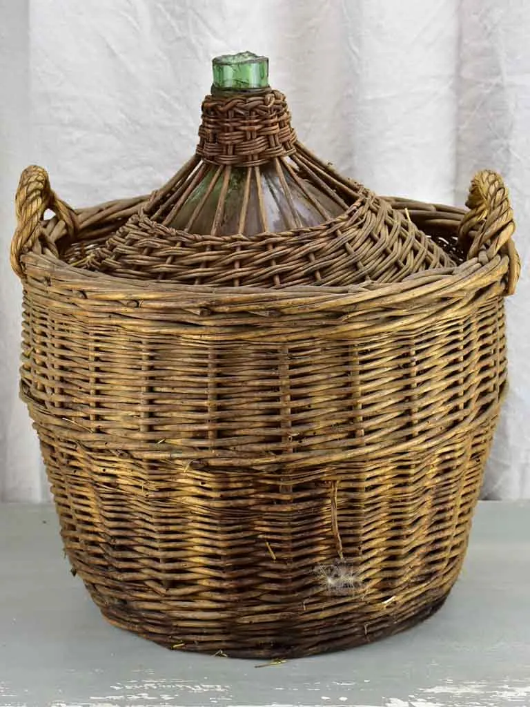 Very large antique French demijohn in a basket